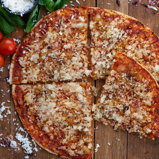 vegan caramelised onion pizza with vegan cheese, basil, and tomato served on a wooden surface