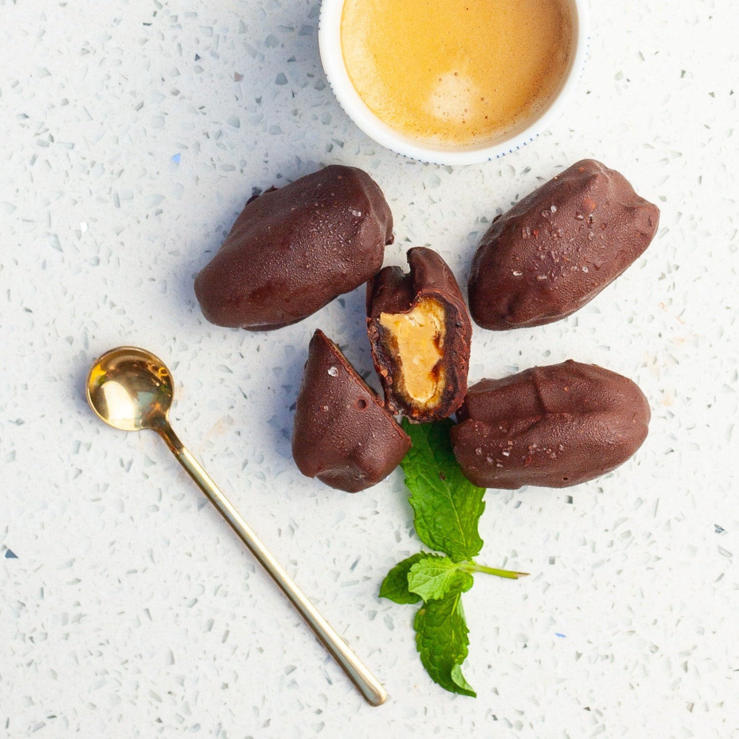 Chocolate covered vegan date energy balls with peanut butter inside, served on a speckled plate.