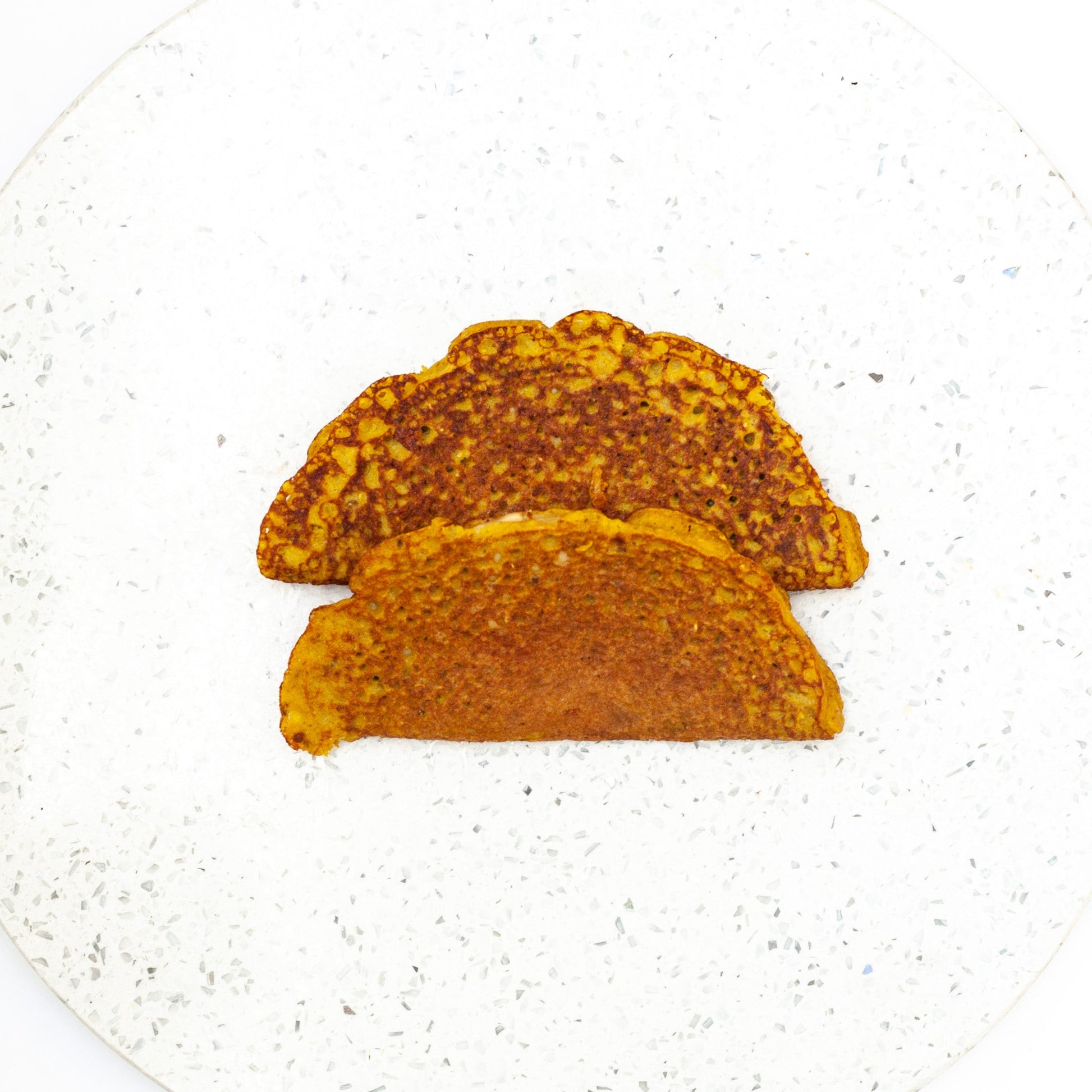 Two vegan mung bean omelette on a white textured plate.