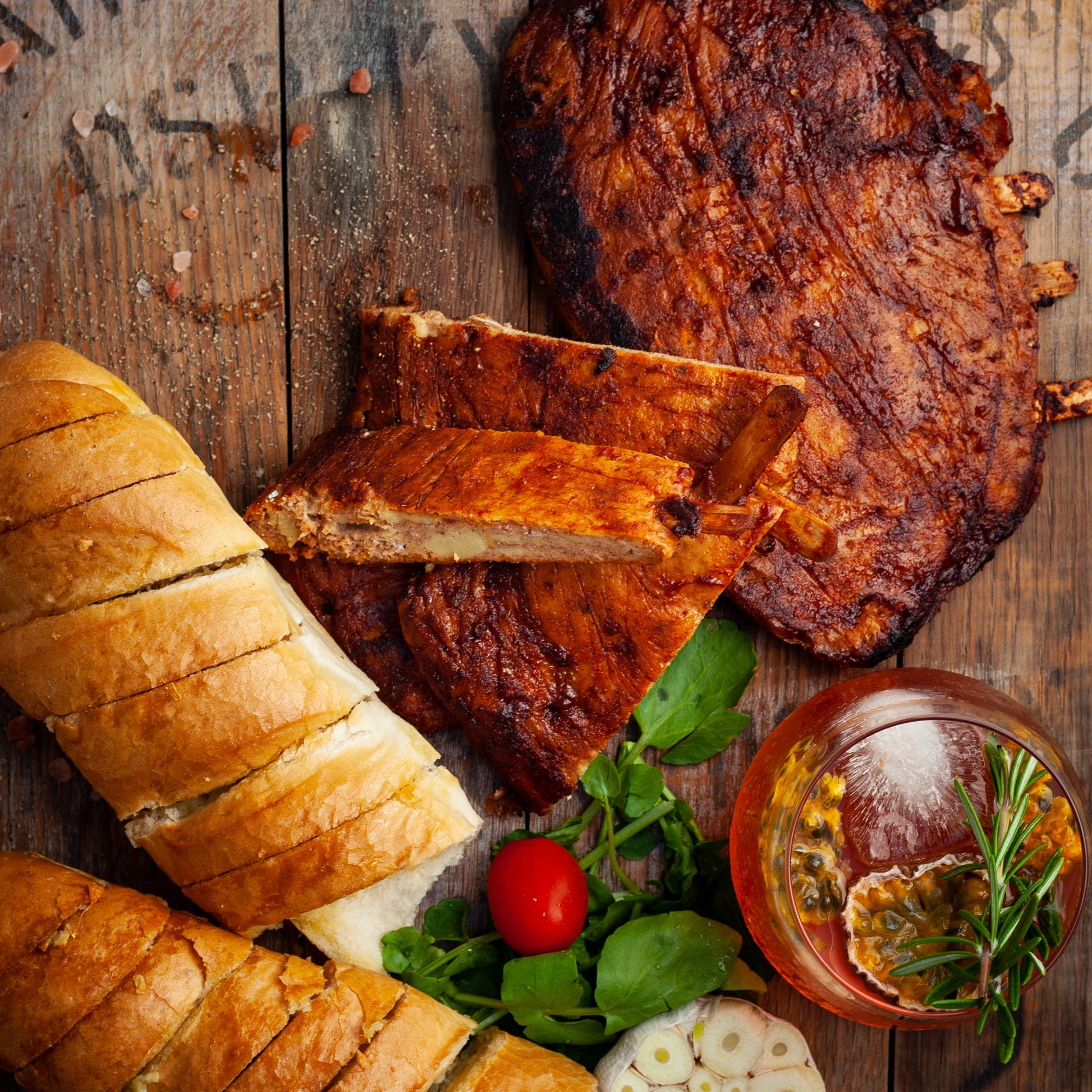 vegan plant-based BBQ ribs with garlic bread slices and greens on a wooden surface
