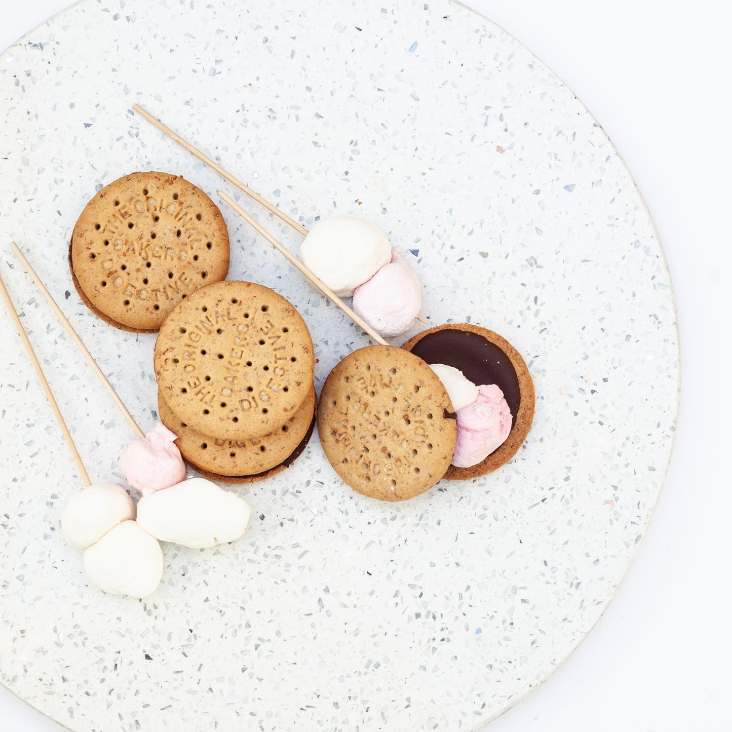 vegan s’mores and marshmallow skewers on a speckled plate