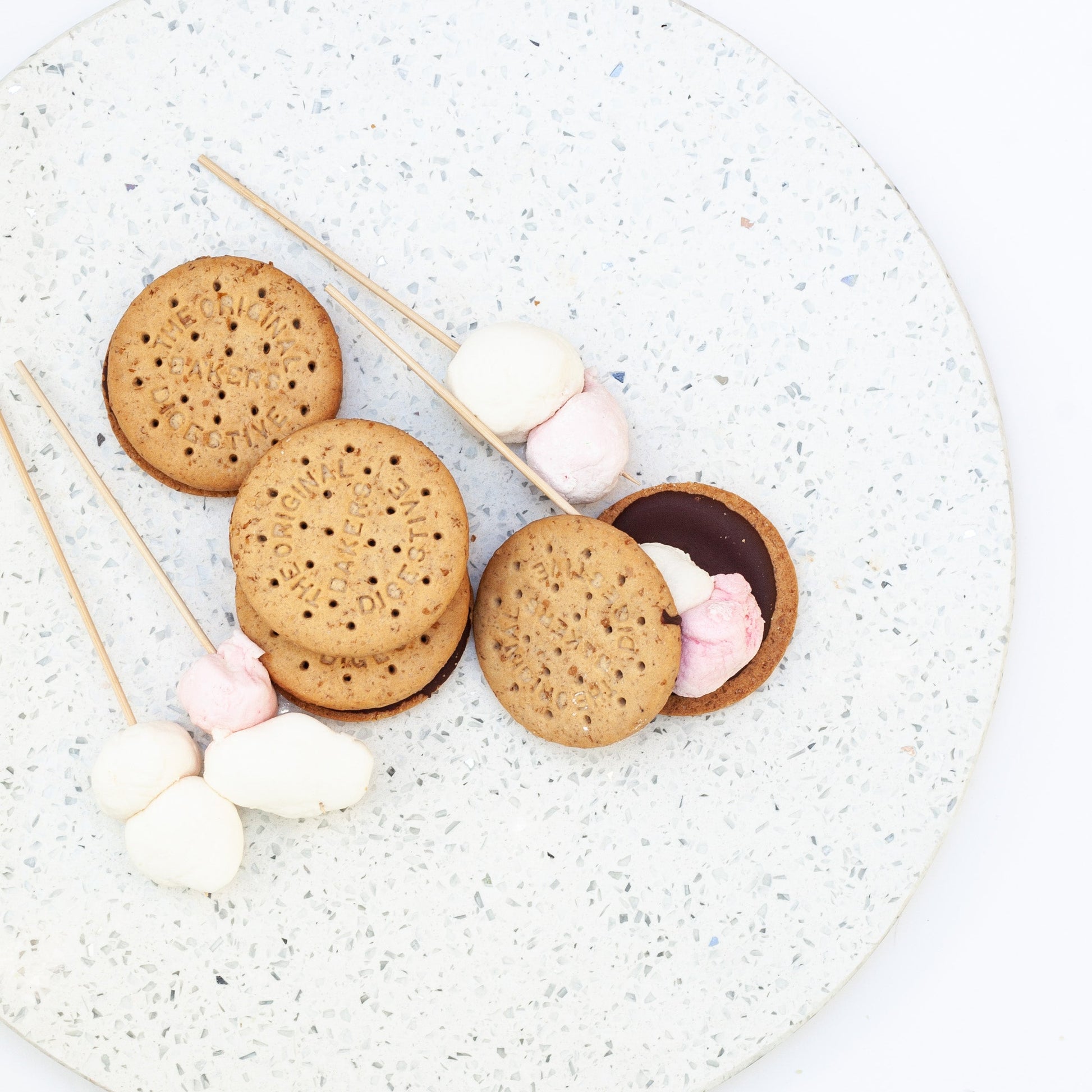 vegan s’mores and marshmallow skewers on a speckled plate